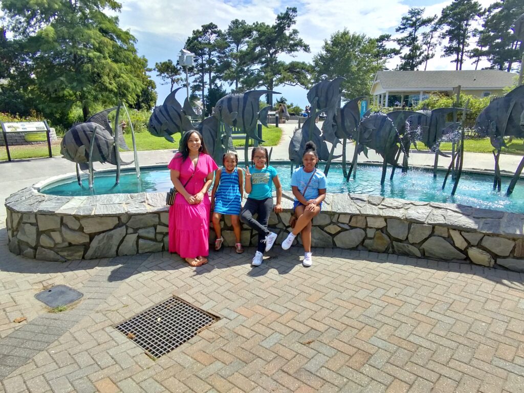 Mother and three girls sitting in front of outdoor fountain